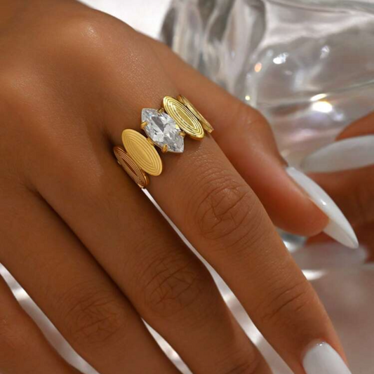 Gold rings with a central diamond on a hand with white nail polish.