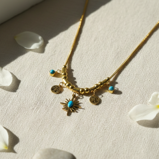 Gold necklace with charms on a light fabric background