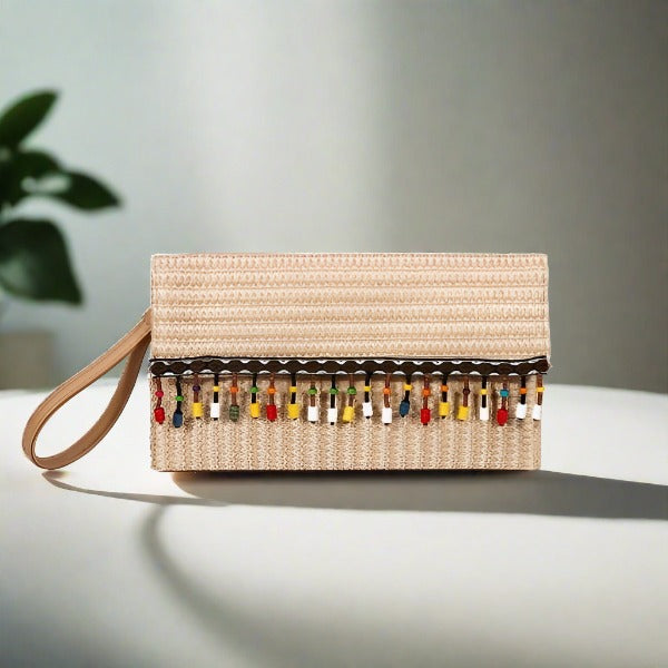 A beige straw square clutch with white lace trim and tassel detailing, displayed against a shadowed background.