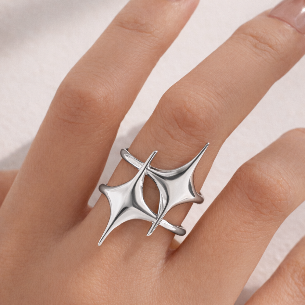 Silver ring with a unique design on a finger against a neutral background