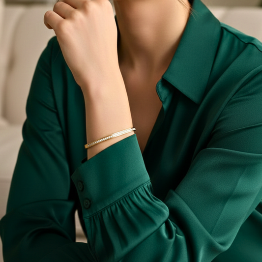 Person wearing a green shirt with rolled-up sleeves and a gold bracelet.