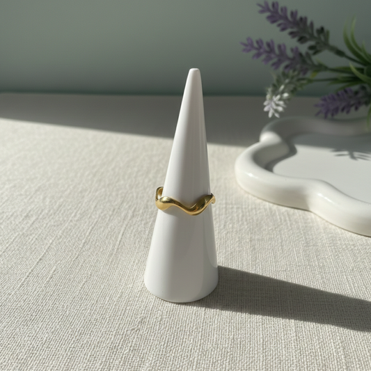 Gold ring on a white cone-shaped jewelry stand with a soft background
