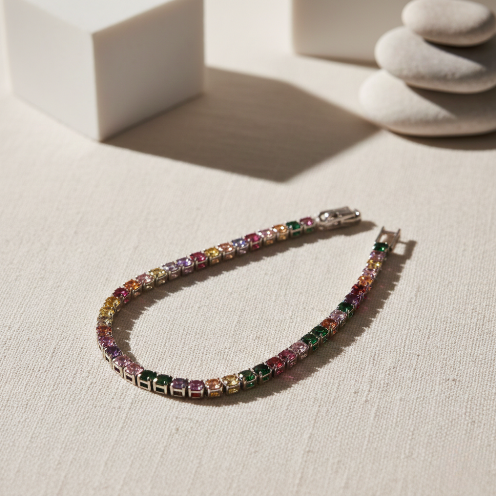 Multicolored gemstone white tennis bracelet on a light fabric surface.
