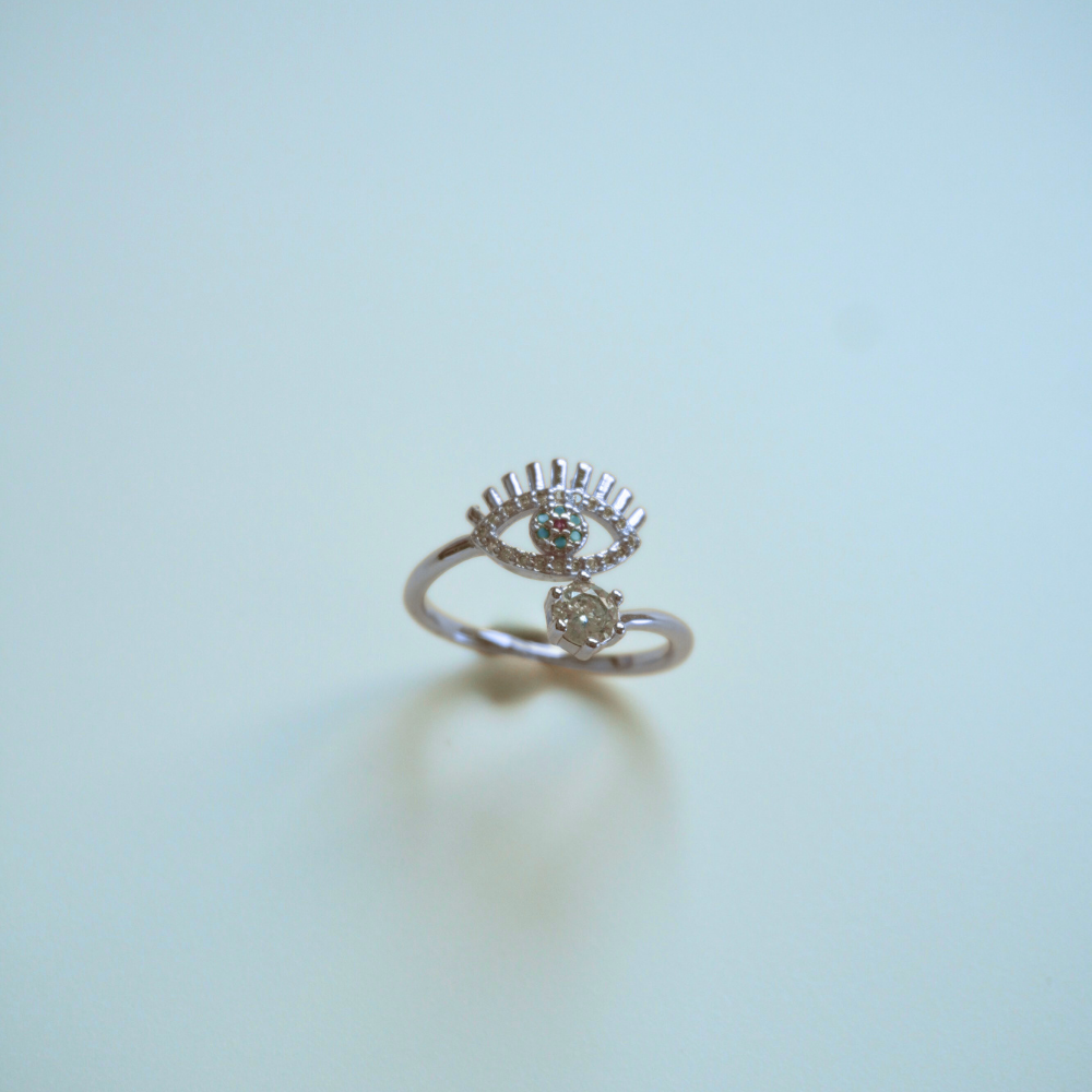 Silver ring with eye design on a light blue background