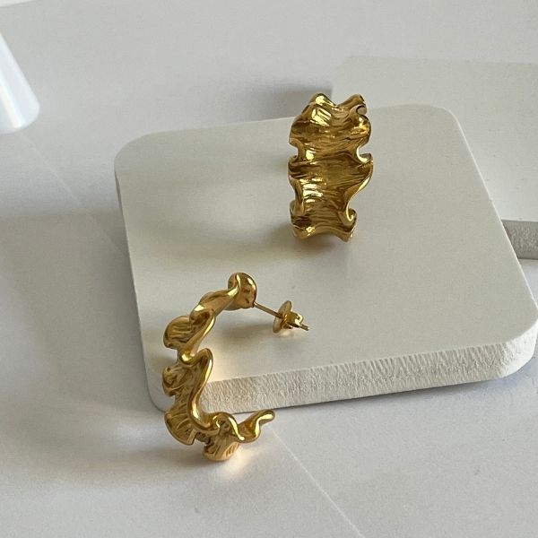 A pair of gold-plated retro style stud earrings with a textured, ruffled design displayed on a white surface.