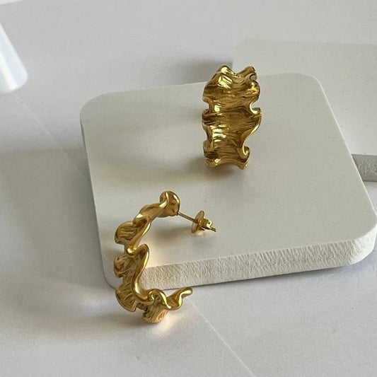 A pair of gold-plated retro style stud earrings with a textured, ruffled design displayed on a white surface.