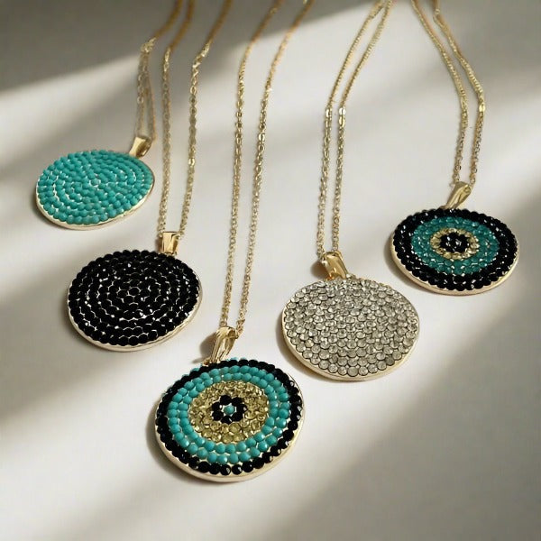 A collection of gold-plated necklaces with disk-shaped pendants. Some pendants have a black and white pattern, while others feature a geometric design with zircon stones.