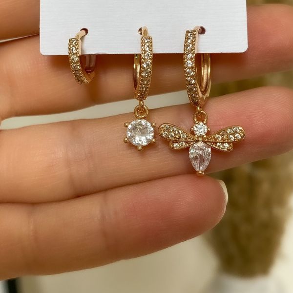 A pair of gold-plated hoop earrings adorned with rhinestones, displayed on a card.