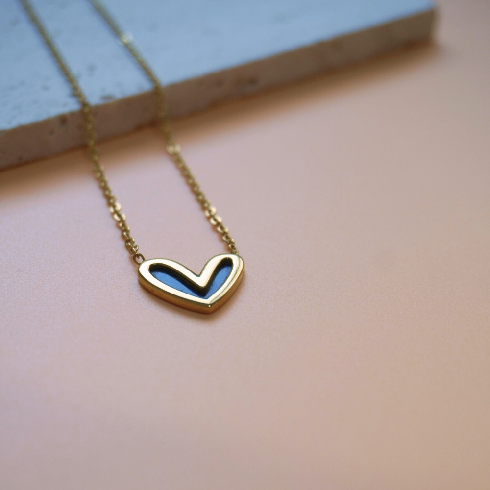 Gold heart-shaped necklace on a soft pink background