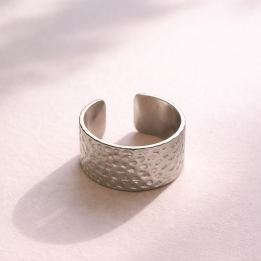 Silver textured cuff bracelet on a light pink background
