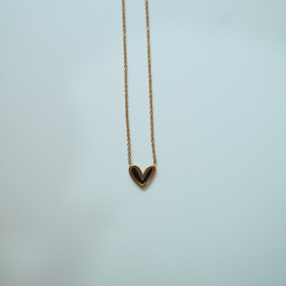 Gold necklace with a heart-shaped pendant on a light blue background