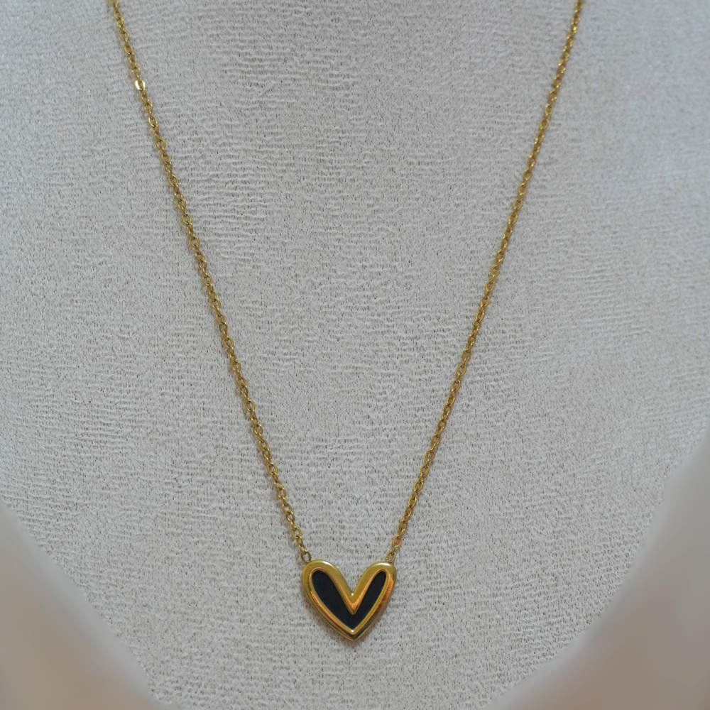 Gold necklace with a heart-shaped pendant on a light gray background