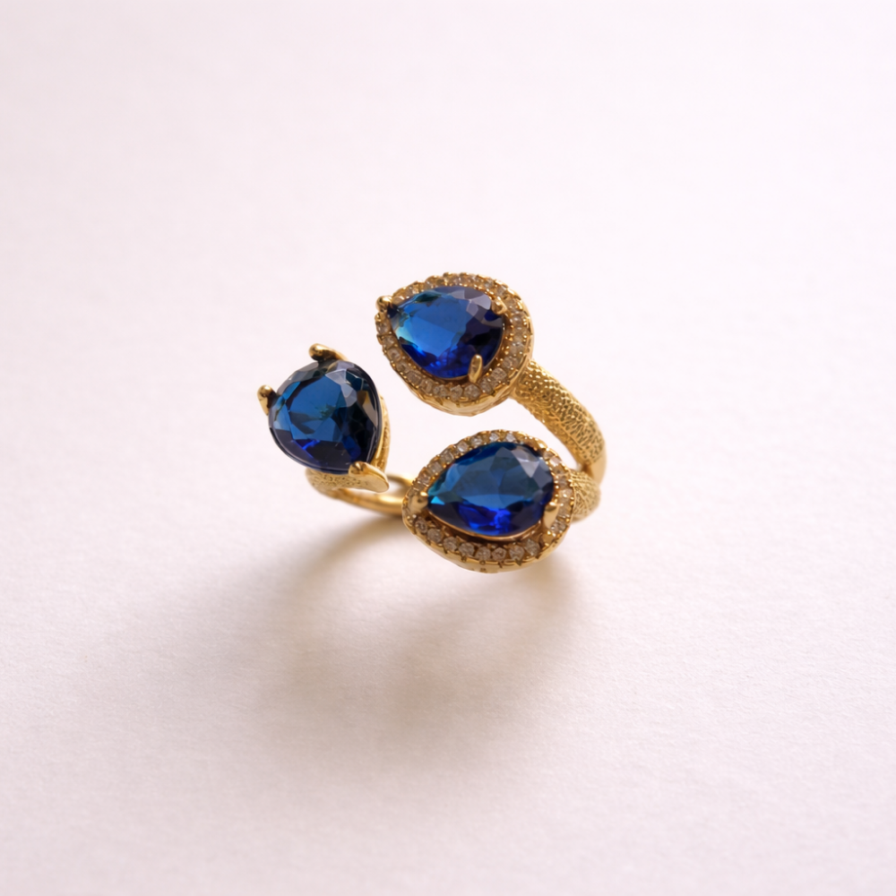 Gold ring with blue gemstones on a light pink background