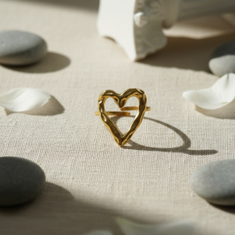 Gold heart-shaped ring on a textured surface with stones