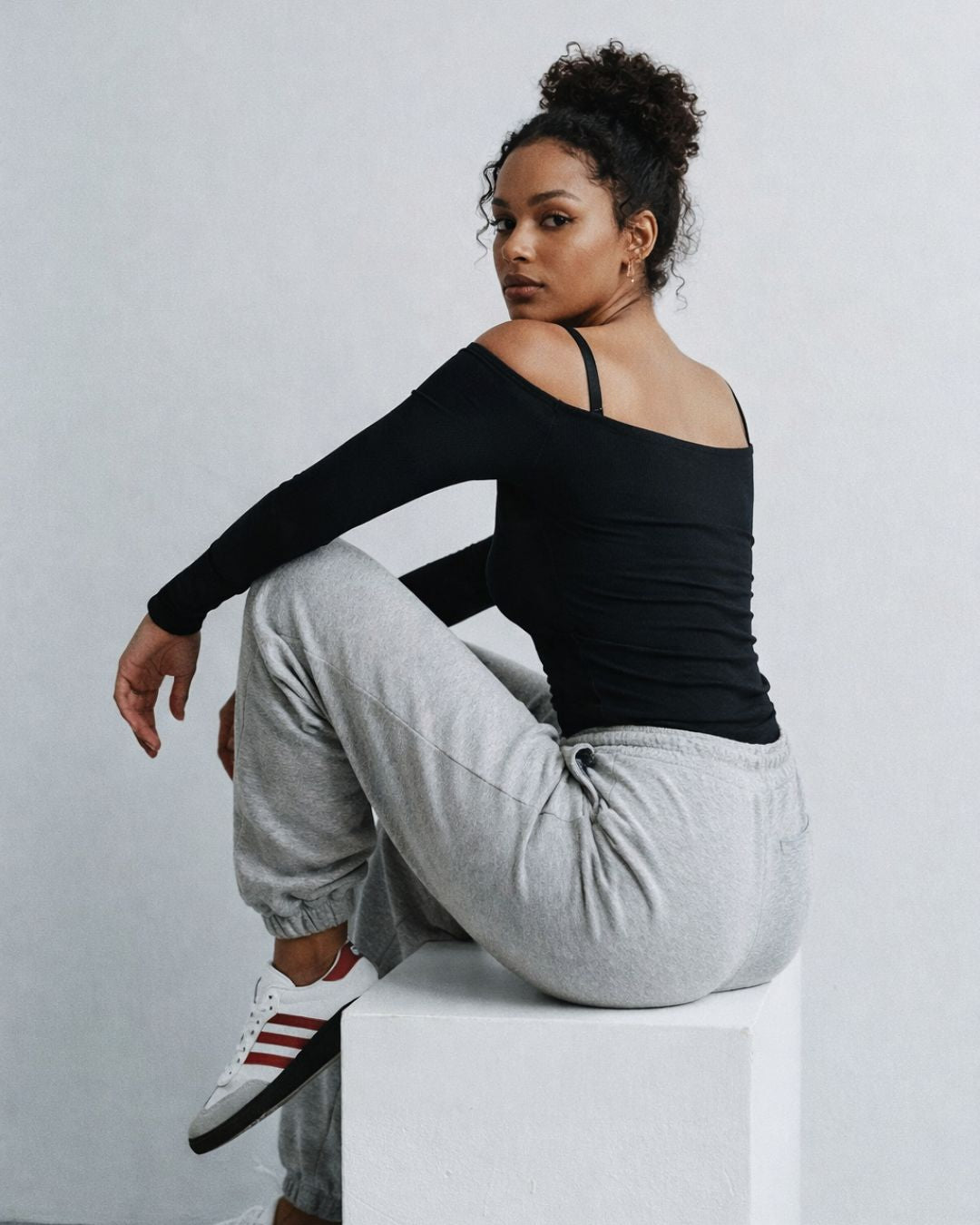 model posing in Elegantix boutique bodysuit and sweatpants against a light gray background