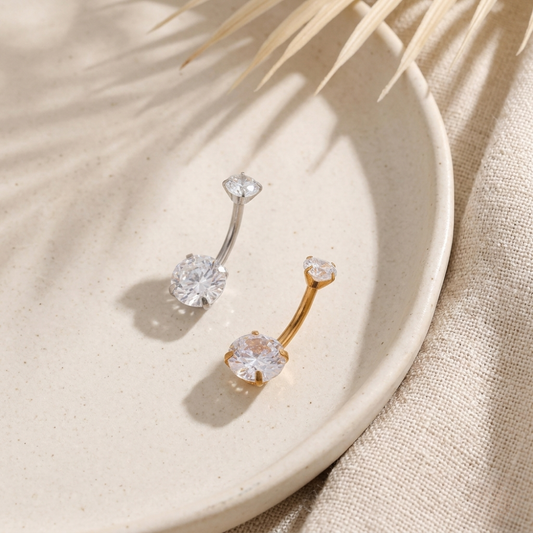 Pair of gold and crystal stud earrings on a beige plate with natural light