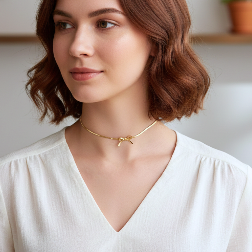 Woman wearing a gold necklace with a bow design indoors
