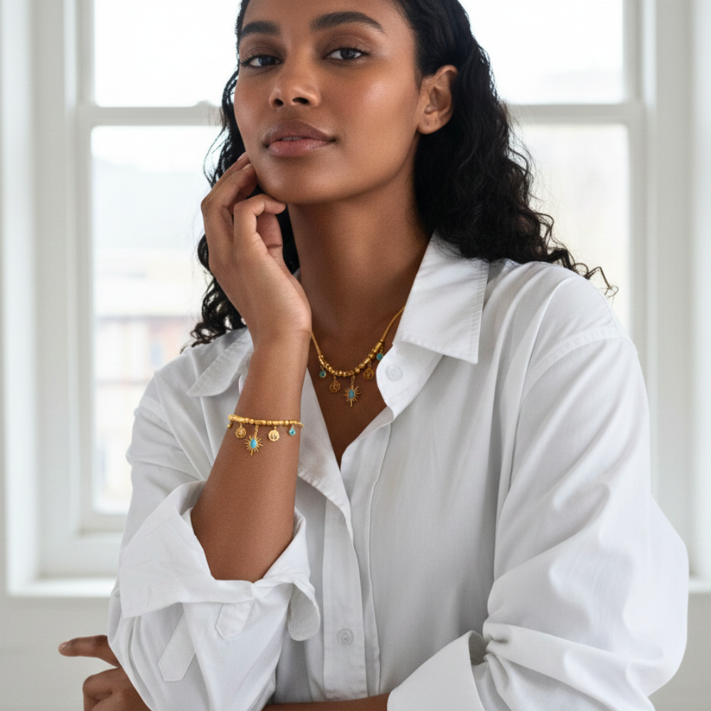 Woman wearing gold jewelry with a white shirt in a bright room