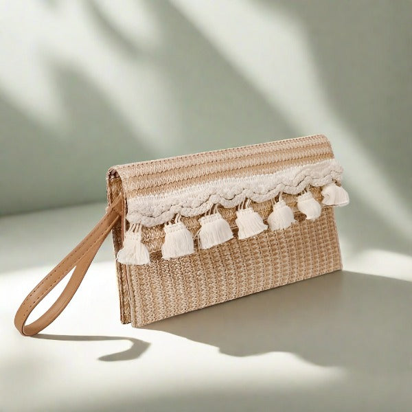 A beige straw square clutch with white lace trim and tassel detailing, displayed against a shadowed background.
