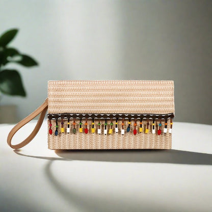 A beige straw square clutch with white lace trim and tassel detailing, displayed against a shadowed background.