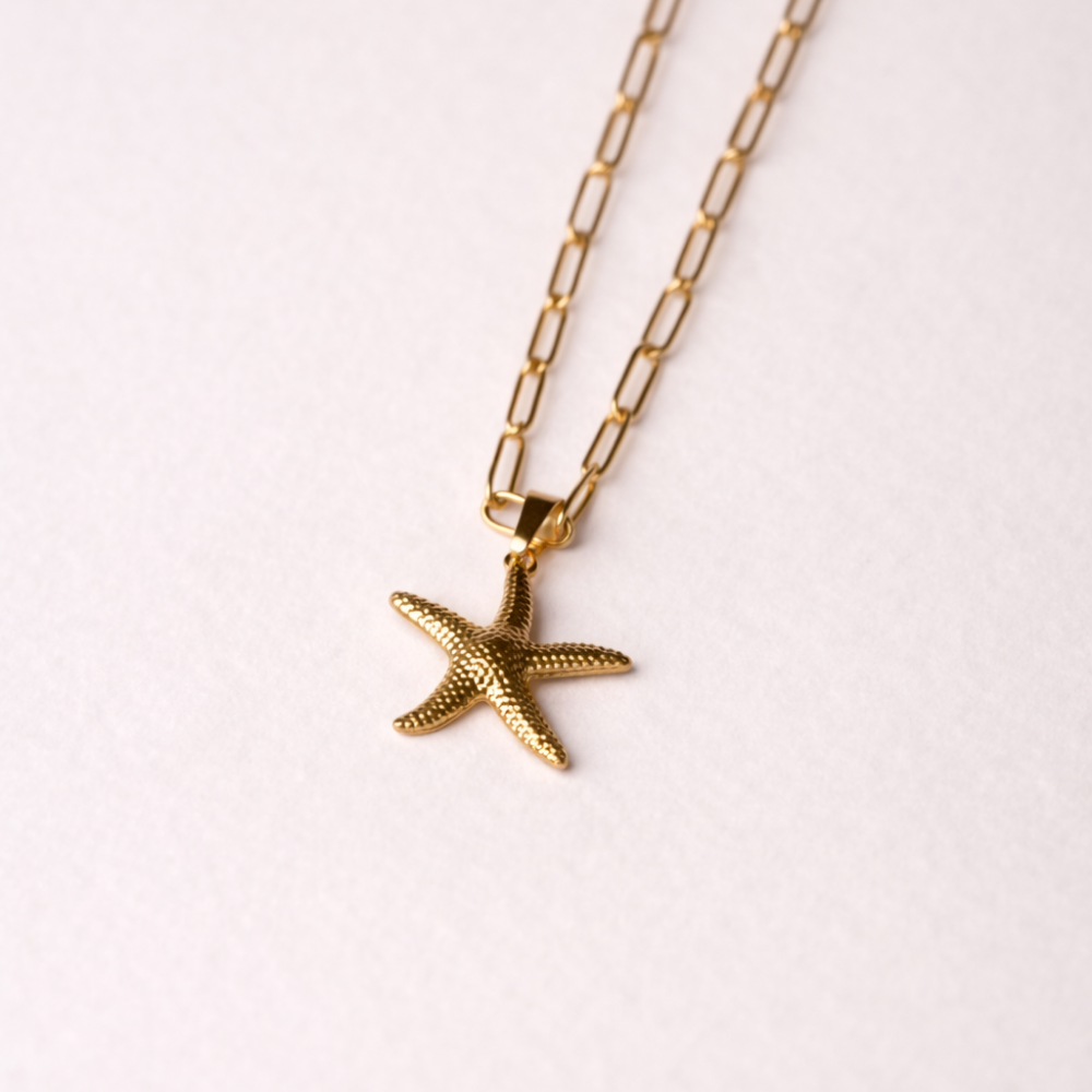 Gold starfish pendant necklace on a white background