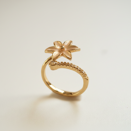 Gold ring with a floral design on a light beige background