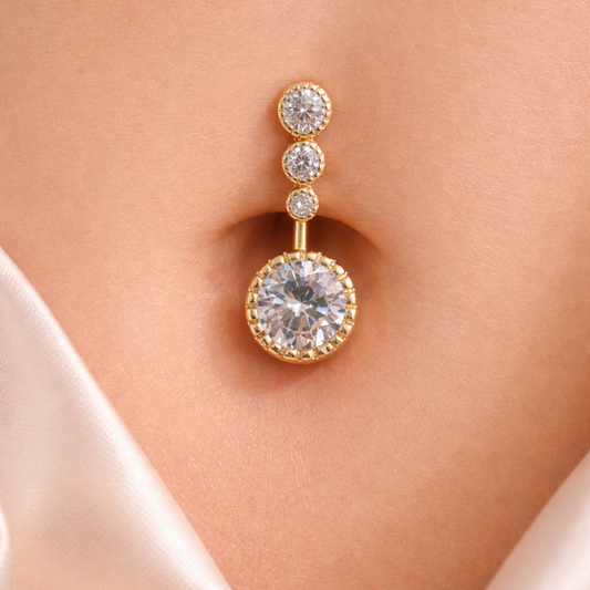 Gold belly-button piercing with three round diamonds on a person's belly