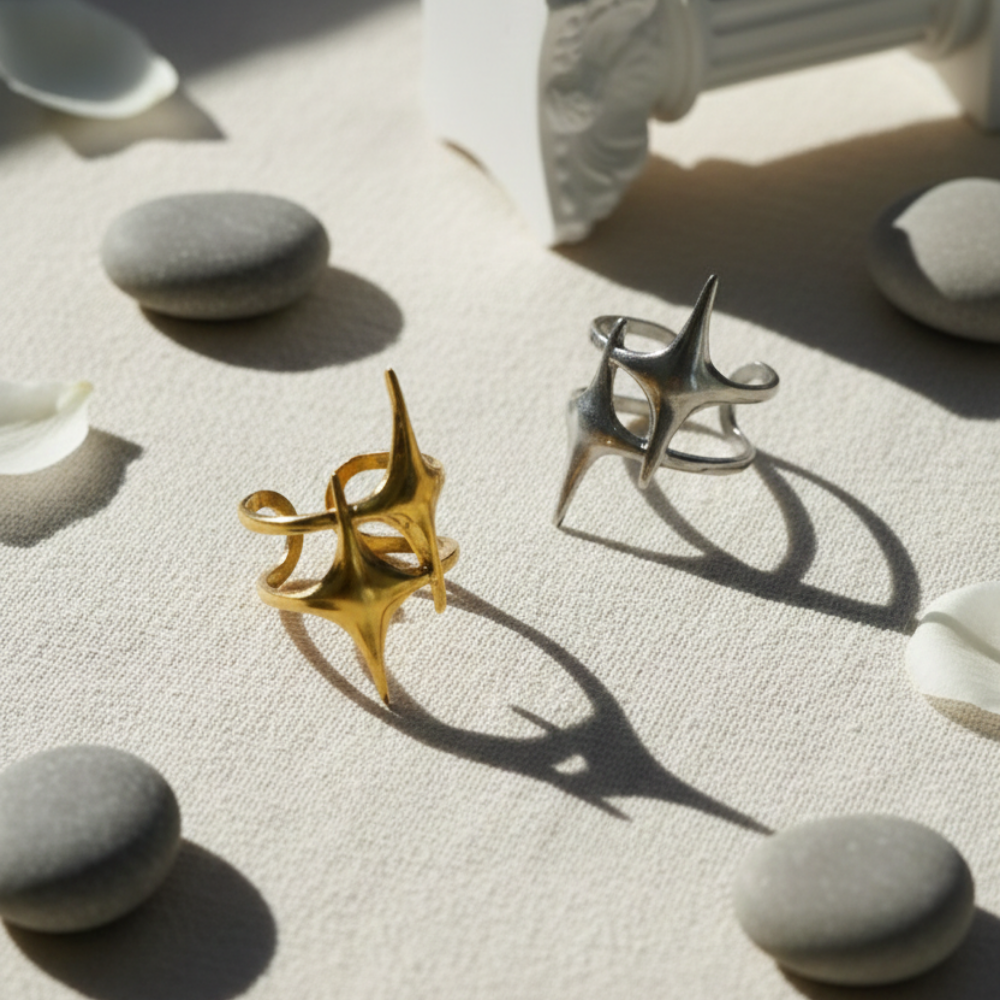 Two metallic rings, one gold and one silver, on a textured surface with stones around.