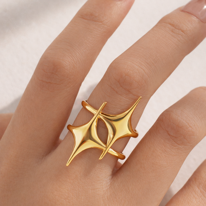 Gold ring with a unique design on a finger against a neutral background