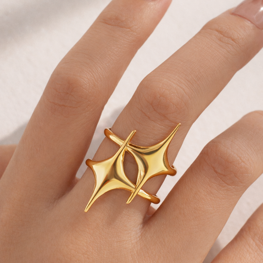 Gold ring with a unique design on a finger against a neutral background