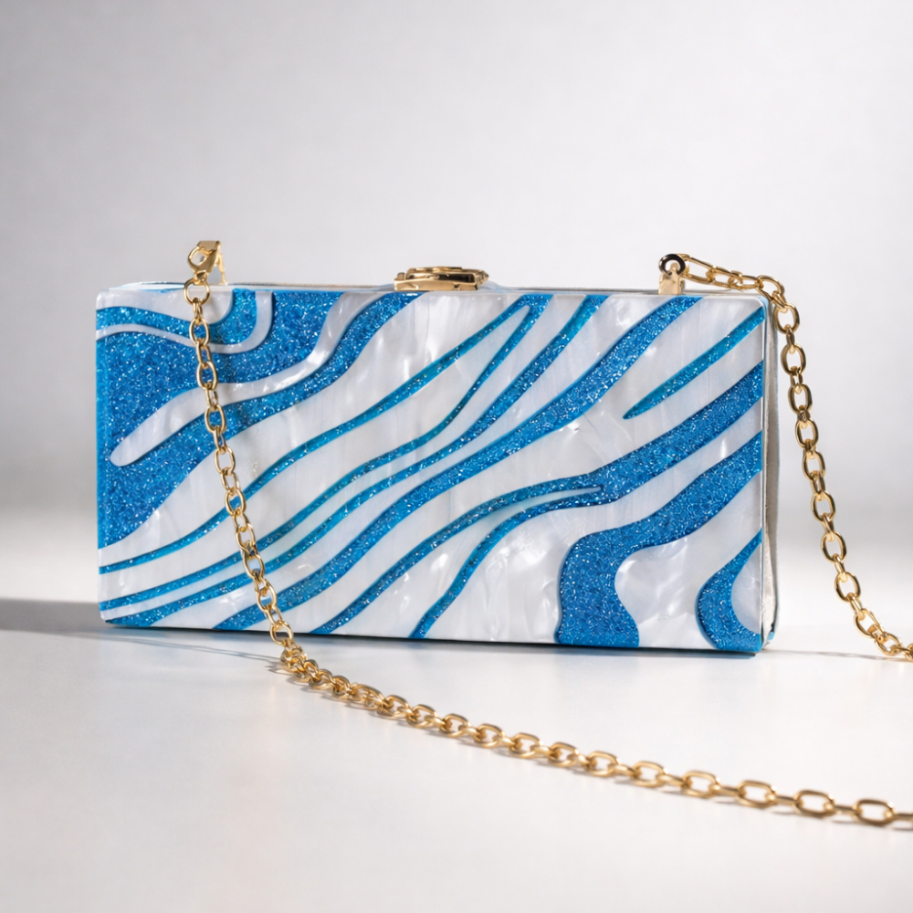 Blue and white patterned clutch bag with a gold chain on a light gray background
