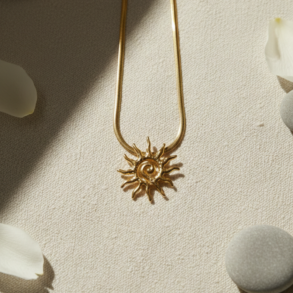 Gold sun-shaped pendant necklace on a textured surface with flowers