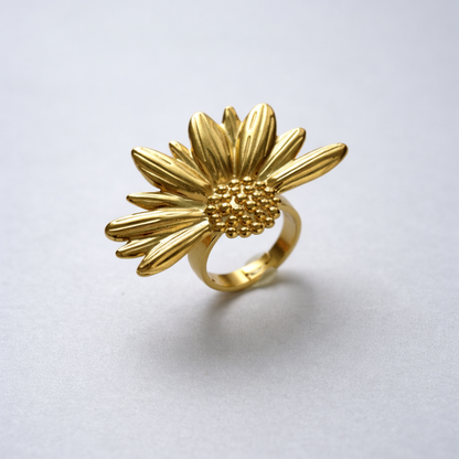 Gold sunflower-shaped ring on a light gray background