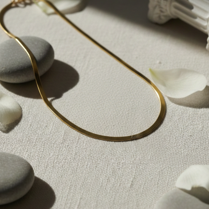 Gold necklace on a textured surface with stones and petals