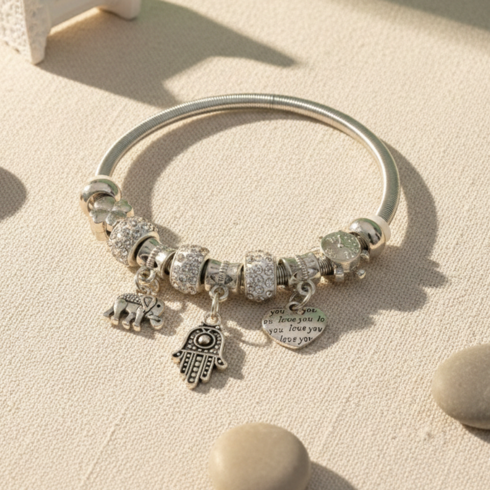Silver bracelet with various charms on a sandy background