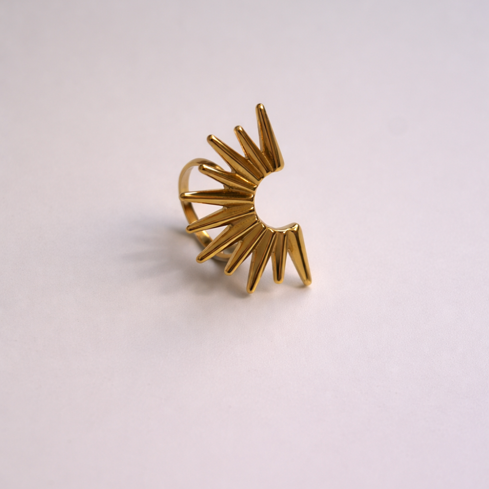 Gold sunburst ring on a light pink background