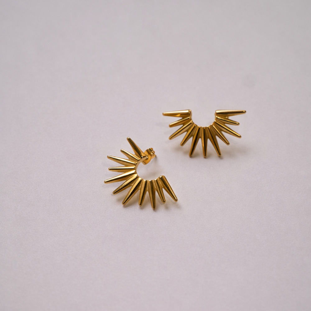 Pair of gold spike earrings on a light gray background