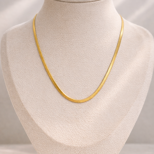 Gold necklace on a mannequin bust against a neutral background