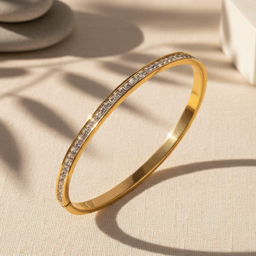 Gold bracelet with embedded stones on a beige fabric background