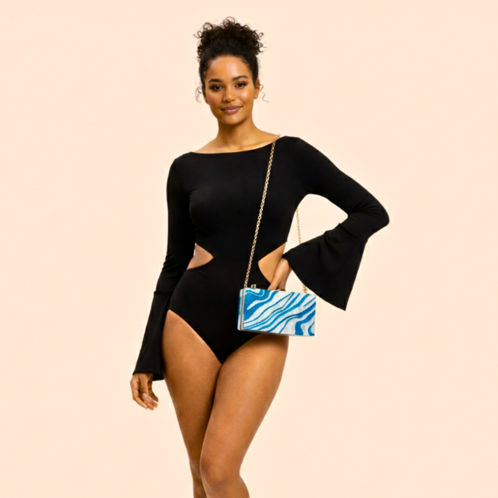 Woman in a black outfit holding a blue and white patterned handbag on a beige background