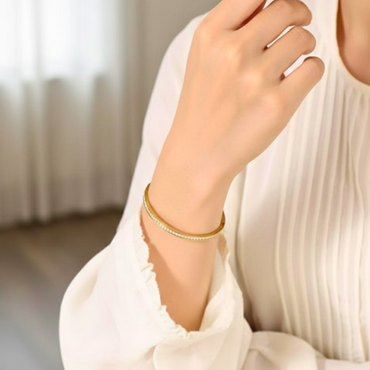 Close-up of a hand wearing a gold bracelet with a blurred background