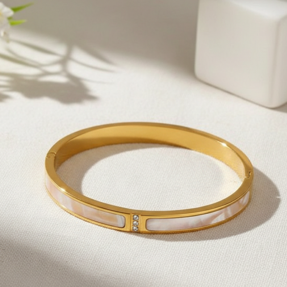 Gold bracelet with a white interior on a light surface