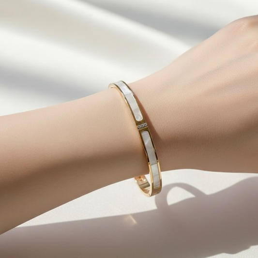 Gold bracelet on a person's wrist against a neutral background