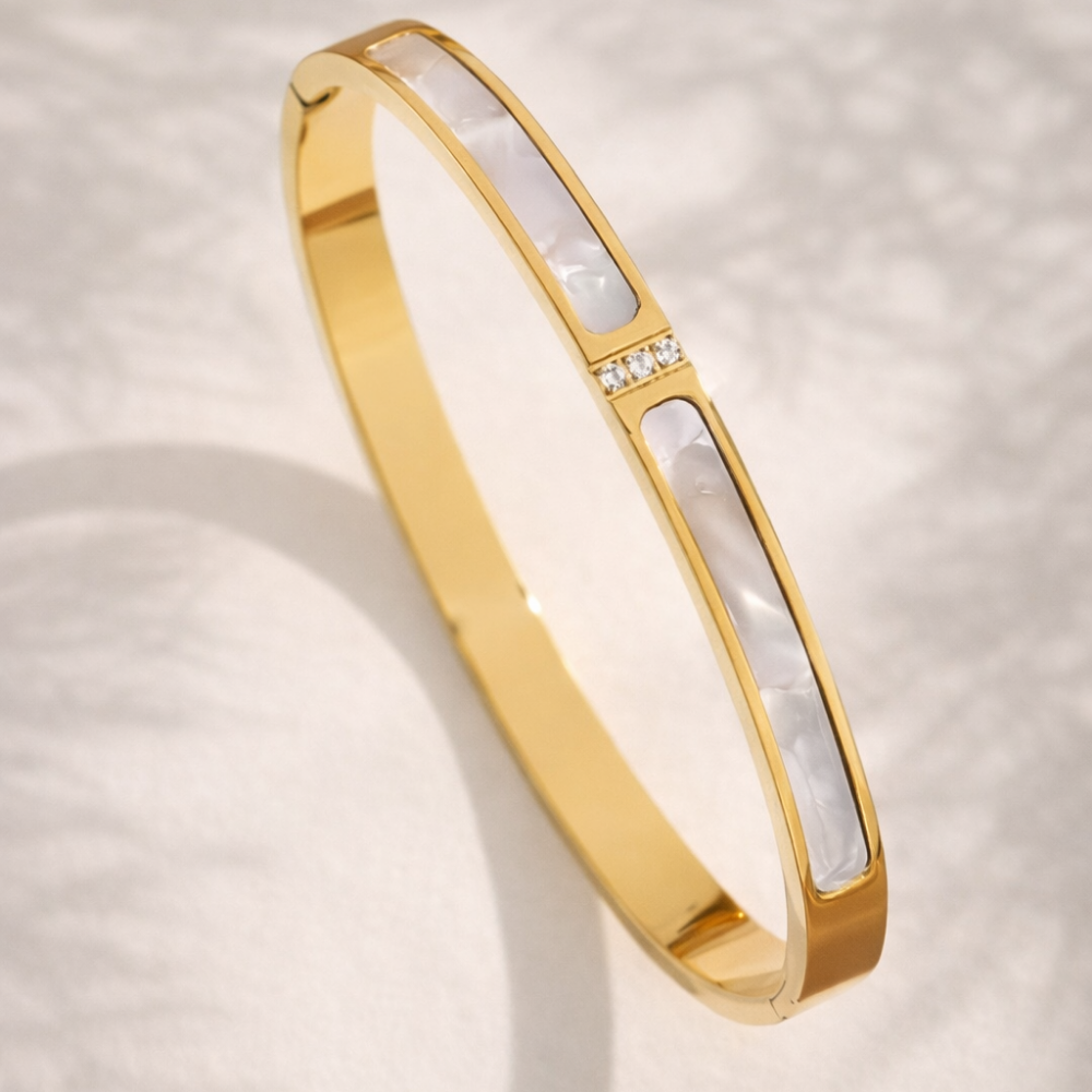 Gold bracelet with a white interior on a light background