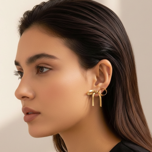 Close-up of a woman wearing gold earrings with a neutral background