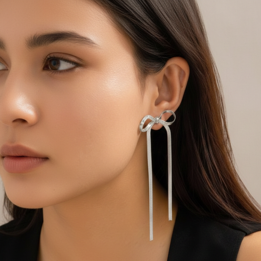 Close-up of a woman wearing a silver bow-shaped earring with a plain background