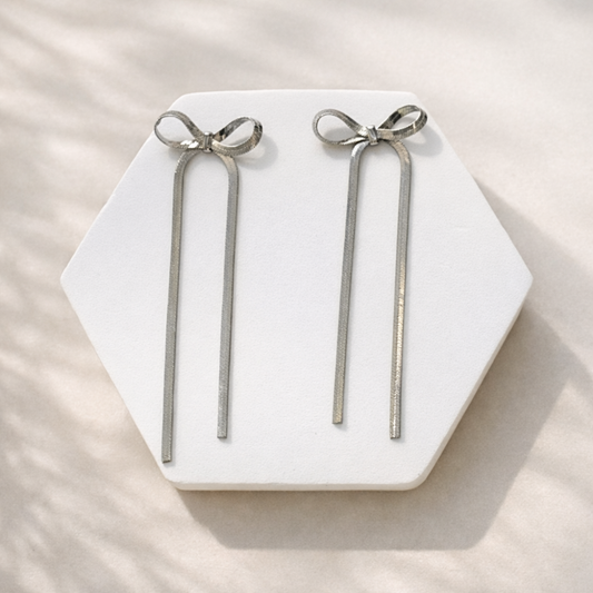 Silver bow-shaped earrings on a hexagonal white stone