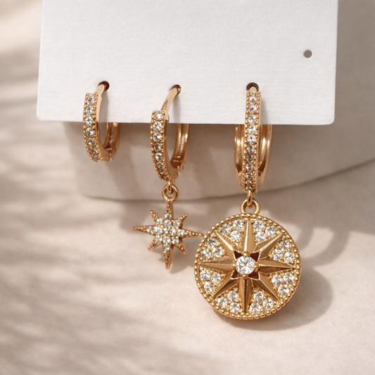 Gold hoop earrings with star and circle designs on a white card.