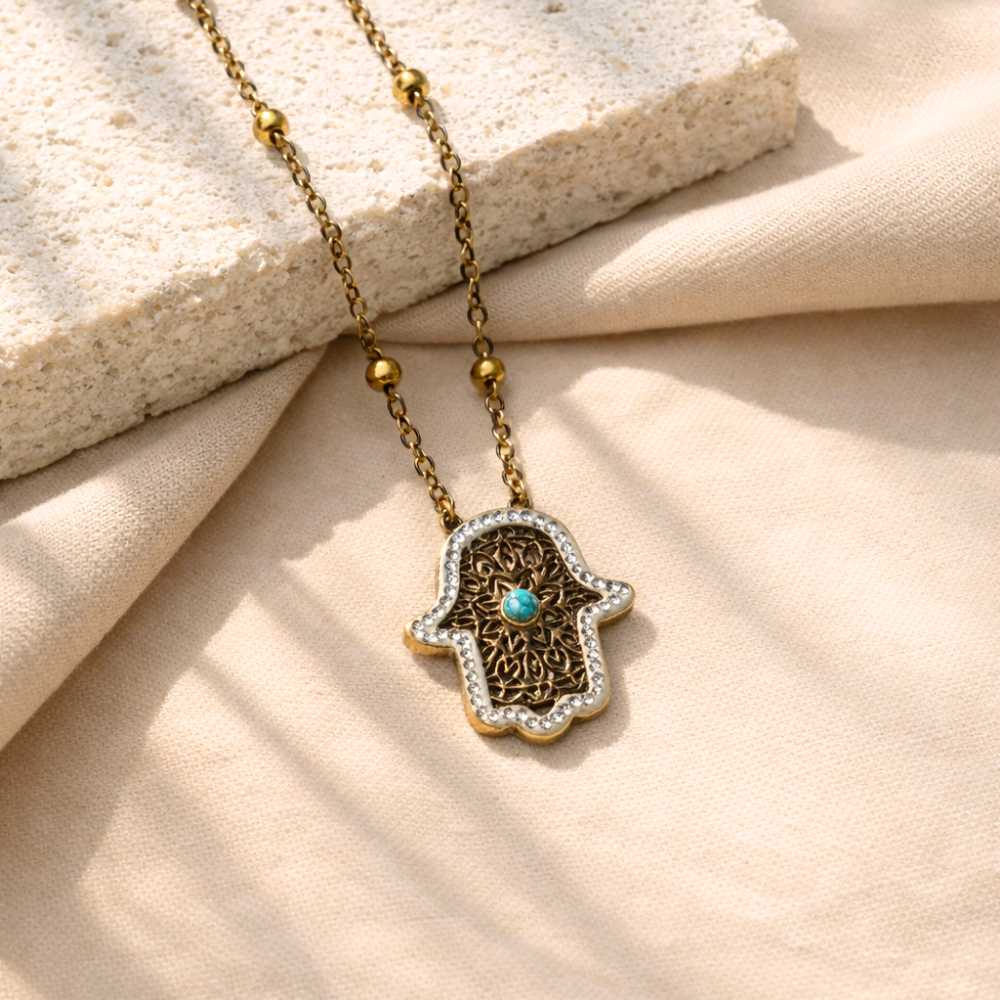 Necklace with Hamsa hand pendant on a beige fabric background