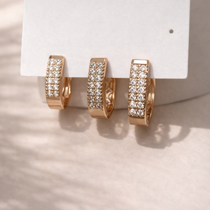 Rose gold hoop earrings with clear gemstones on a white card against a neutral background